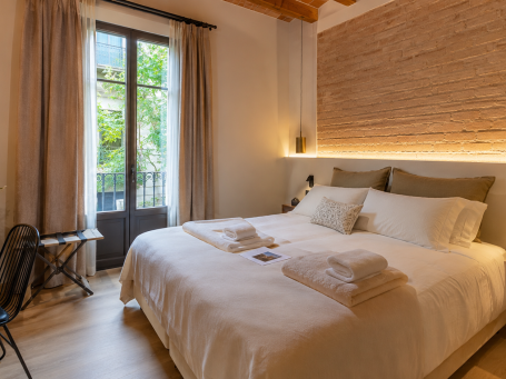 Dormitorio de alojamiento turístico con textiles claros y luz natural
